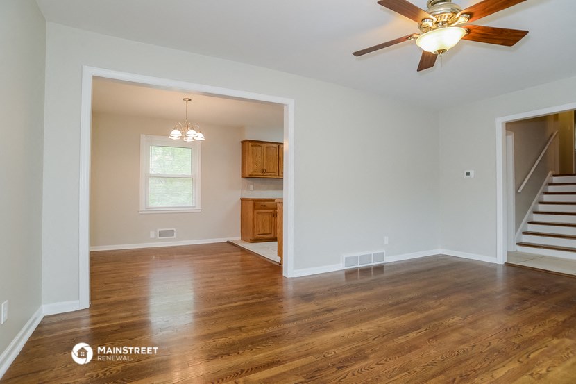 the living room and dining room of an empty house with a ceiling fan