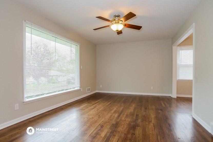 an empty living room with a ceiling fan and a large window
