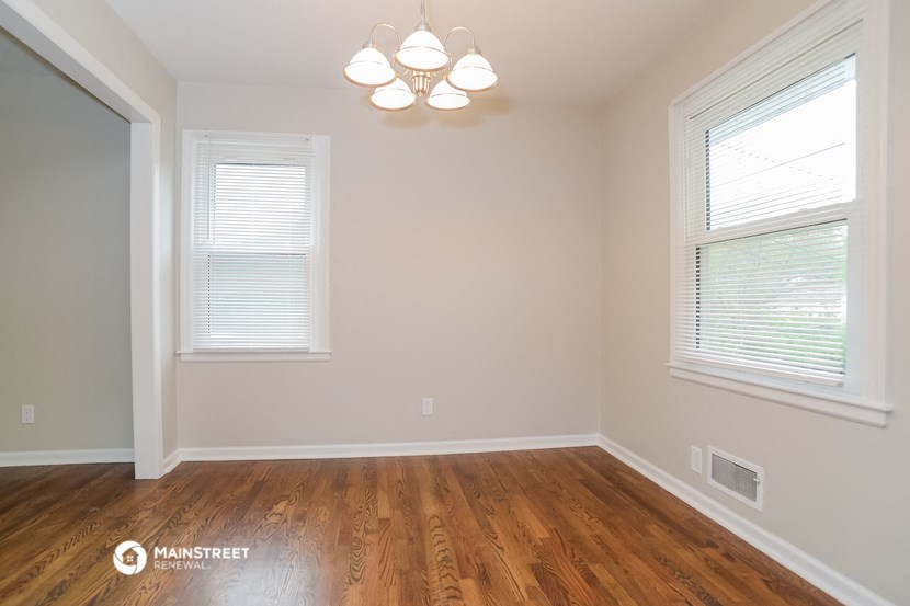 the living room of a home with wood flooring and two windows