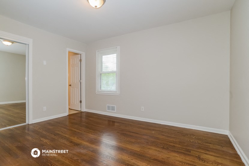 the spacious living room with hardwood flooring and white walls