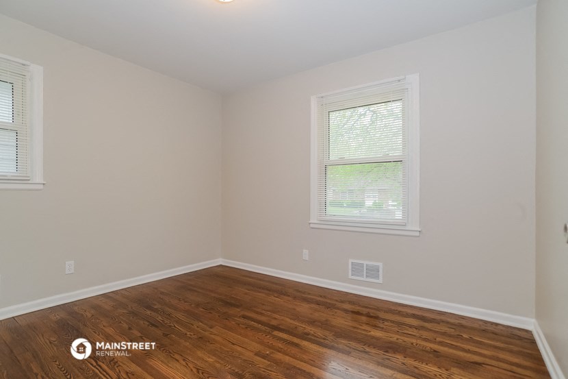the upstairs bedroom with hardwood flooring and two windows