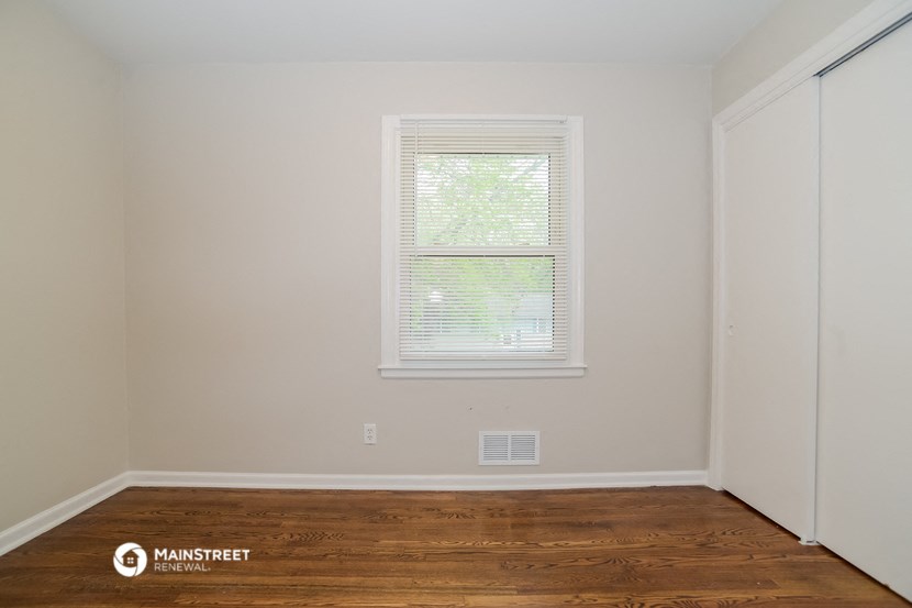 a bedroom with a wood floor and a window