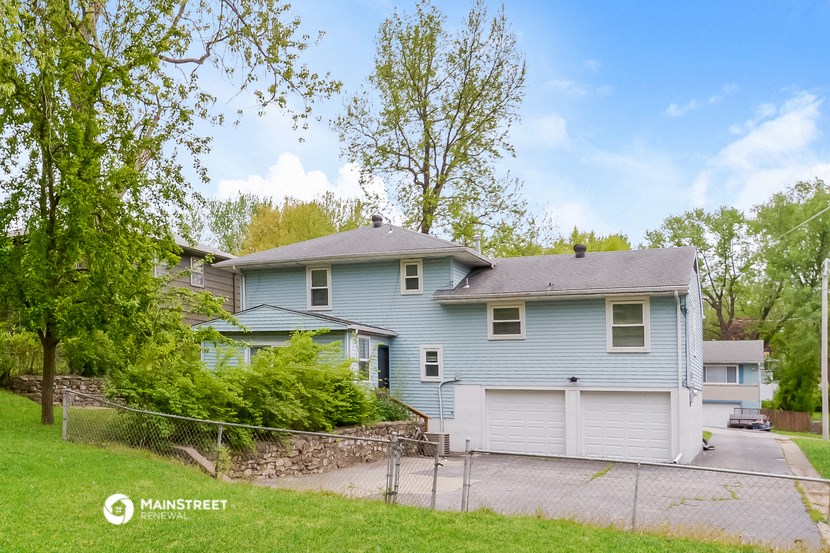 a blue house with a gray roof and a gravel driveway