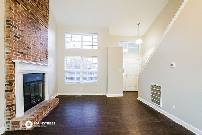 an empty living room with a fireplace and a brick wall