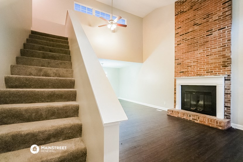an empty living room with stairs and a brick fireplace