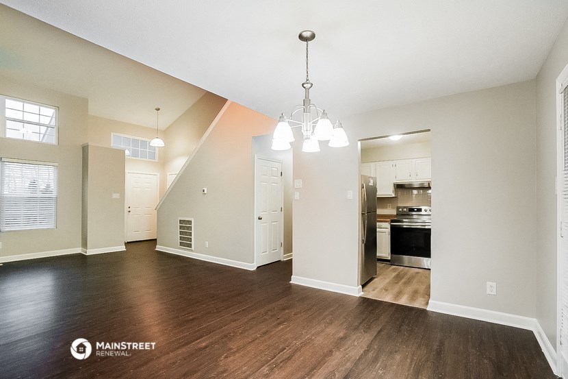 an empty living room with a kitchen in the background