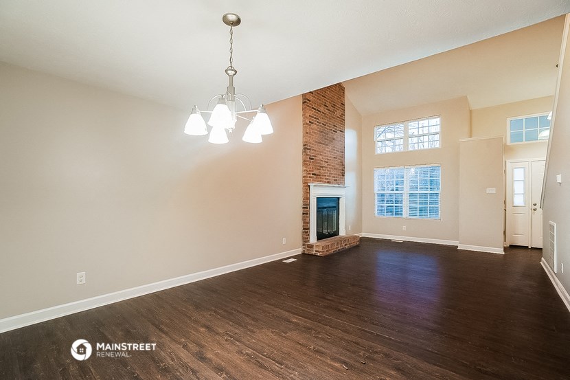 an empty living room with a fireplace and wood flooring