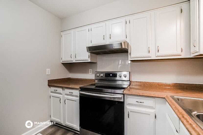 a kitchen with white cabinets and a black stove and