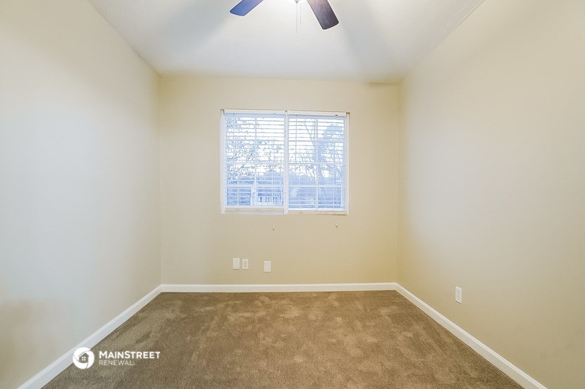 a room with carpet and a window and a ceiling fan