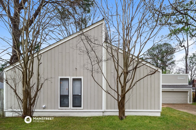 the exterior of a white and gray house with trees