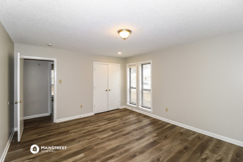 the spacious living room with wood flooring and white walls