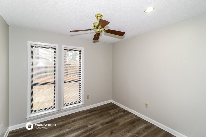 a living room with a ceiling fan and two windows