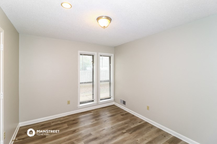 the spacious living room of our apartments offering a large window and wood flooring