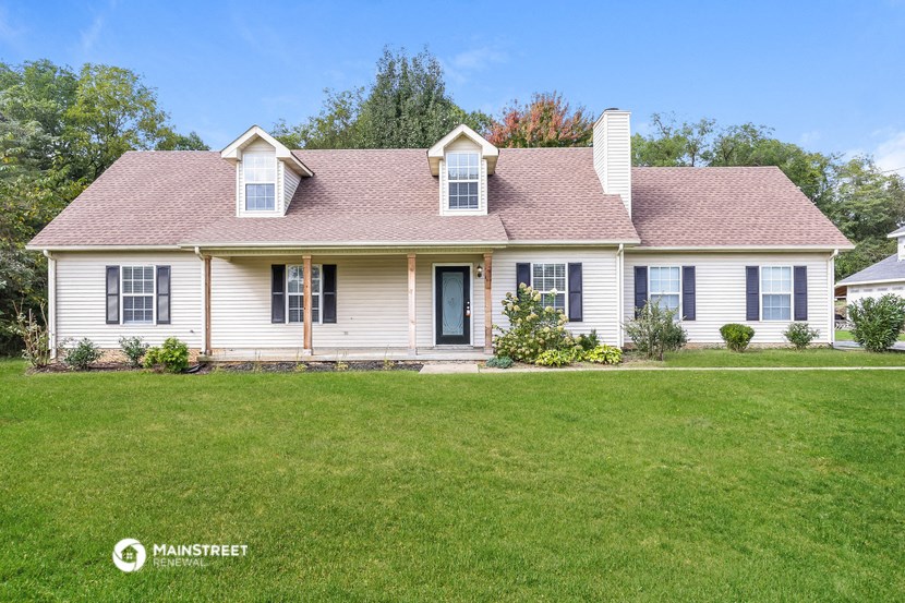 a white house with blue shutters and a green lawn