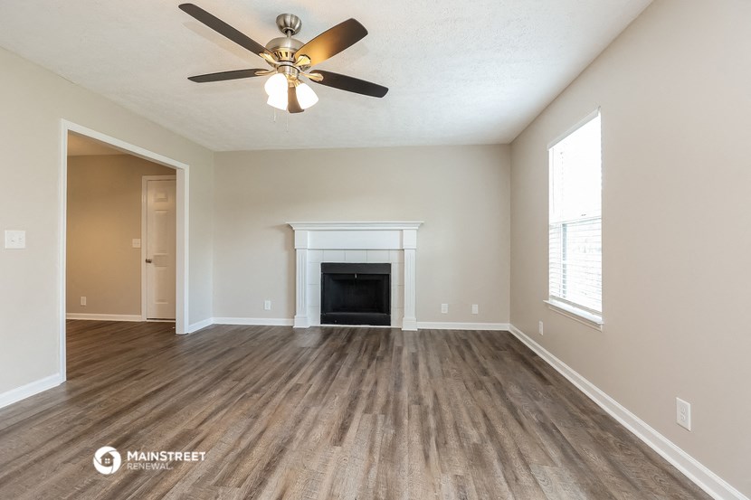 the spacious living room with fireplace and ceiling fan