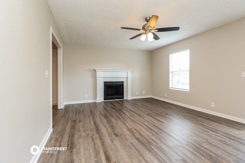 an empty living room with a ceiling fan and a fireplace