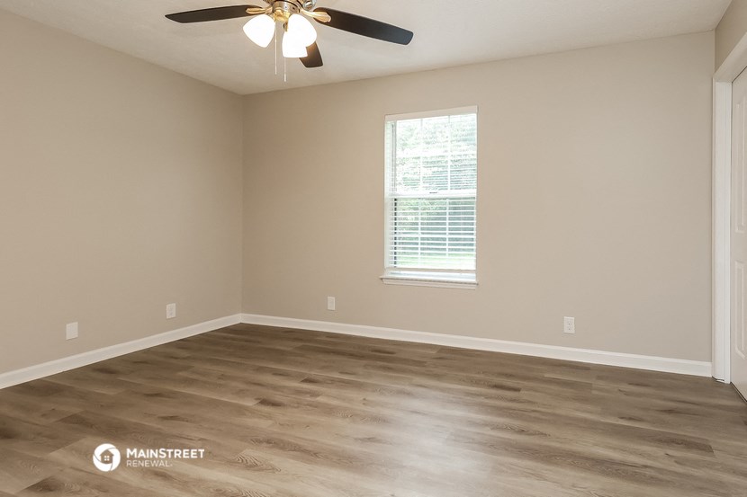 an empty room with wooden floors and a ceiling fan