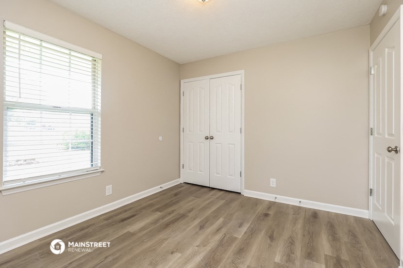 the spacious living room with wood flooring and a window