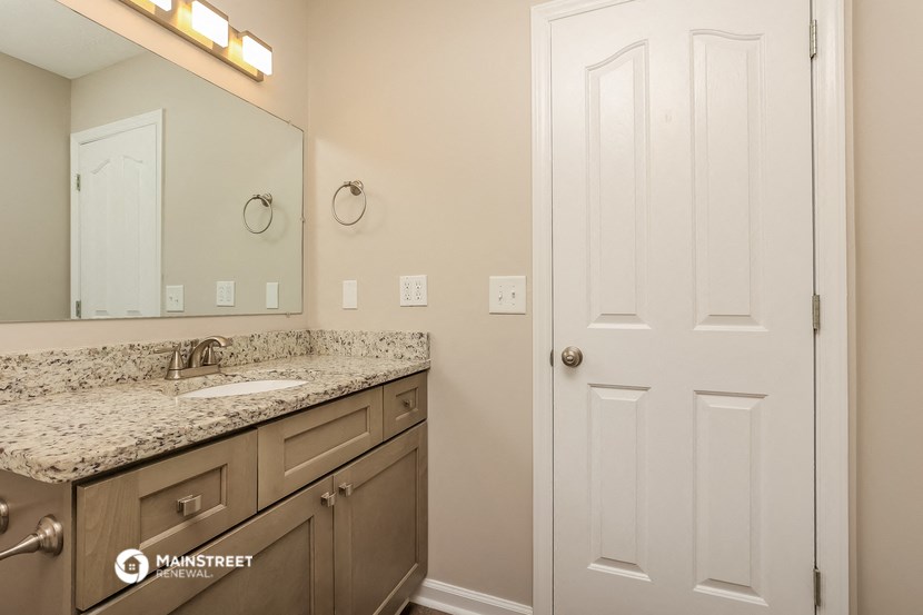 a bathroom with a sink and mirror and a white door