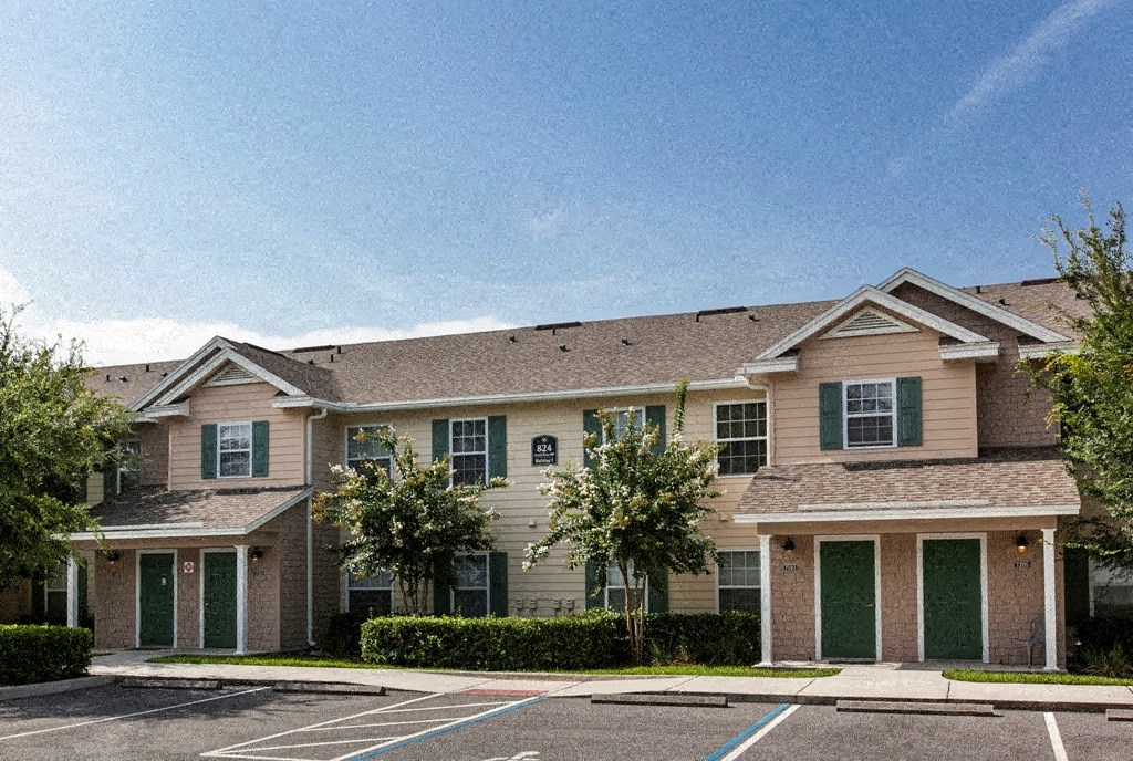 a large house with green doors and a parking lot