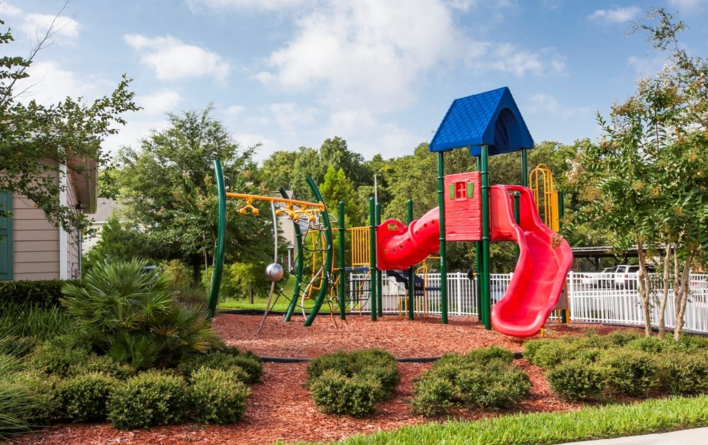 a playground with a red swing set and a blue roof