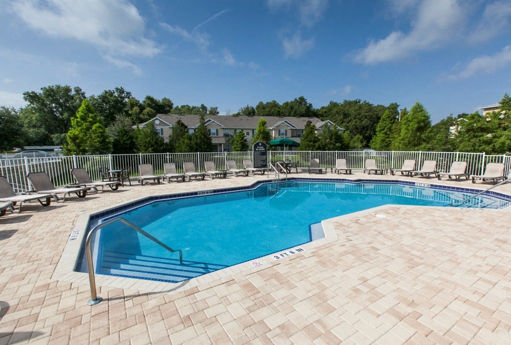 a resort style pool with chairs and a fence around it