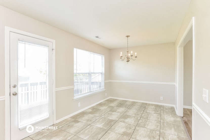 the living room of a home with a large window and a door