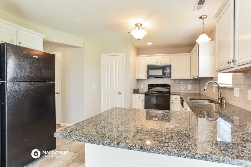 a kitchen with granite counter tops and a black refrigerator