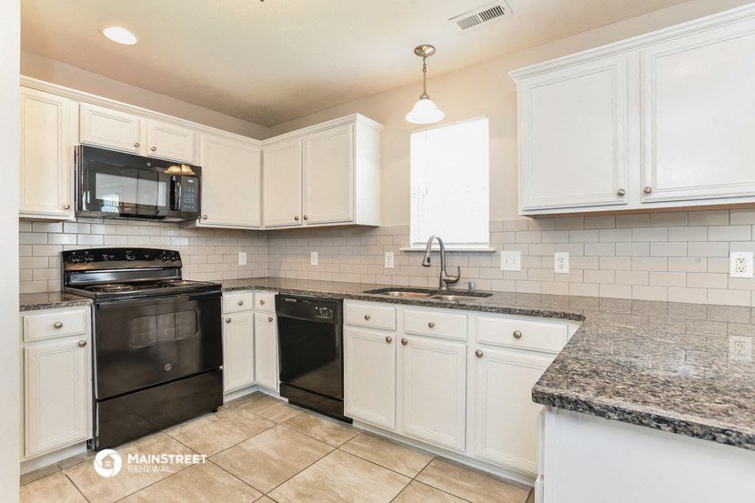 a kitchen with white cabinets and black appliances