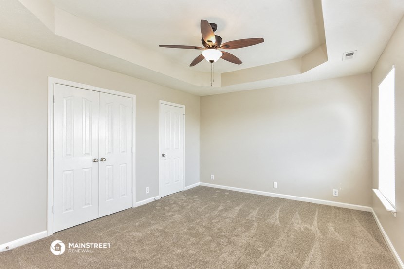 an empty living room with carpet and a ceiling fan
