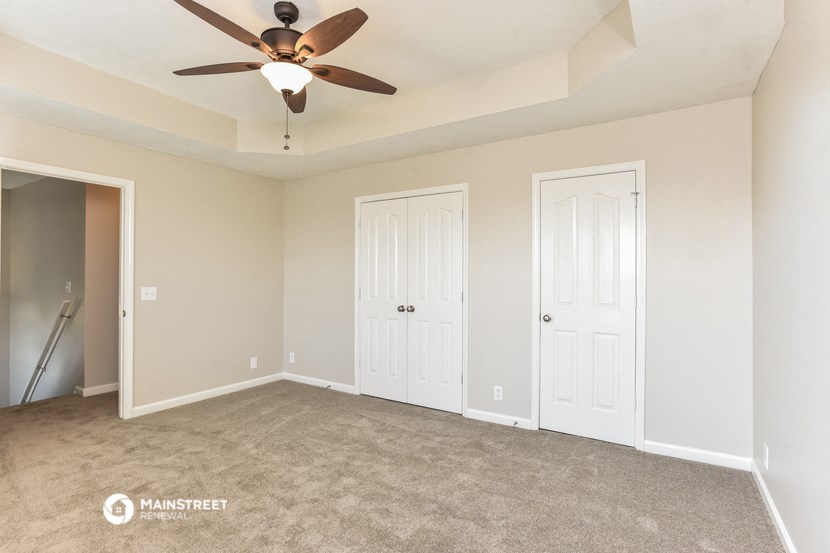 an empty living room with two doors and a ceiling fan