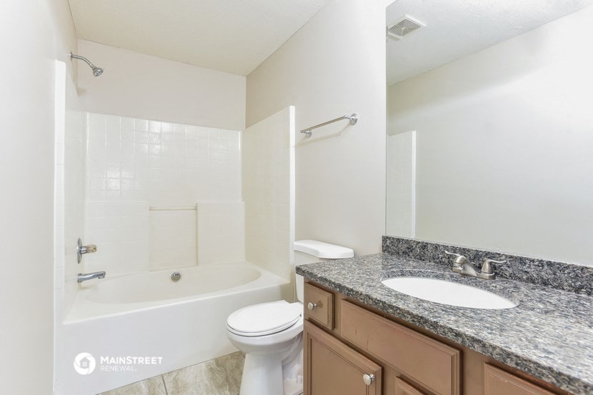 a bathroom with a tub sink and toilet and a mirror
