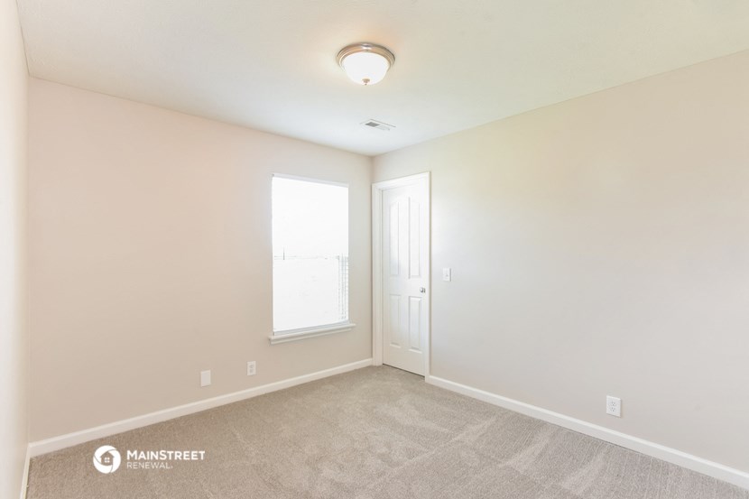 the spacious living room with carpet and a door to the bedroom
