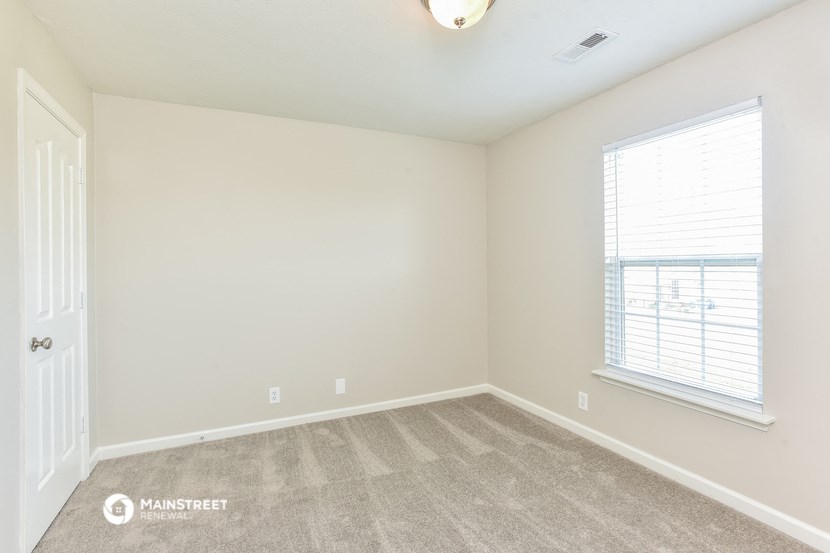 the spacious bedroom with carpeted flooring and a large window
