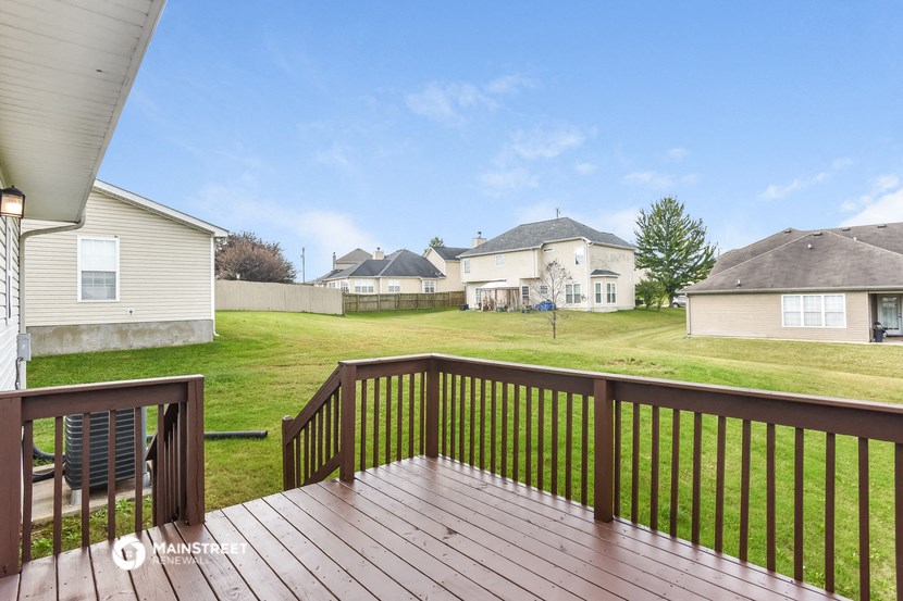 a deck with a yard and houses in the background