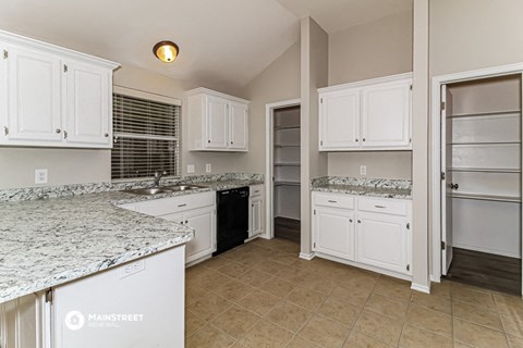 a large kitchen with white cabinets and granite counter tops