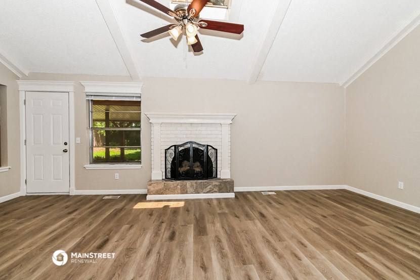 a living room with a fireplace and a ceiling fan