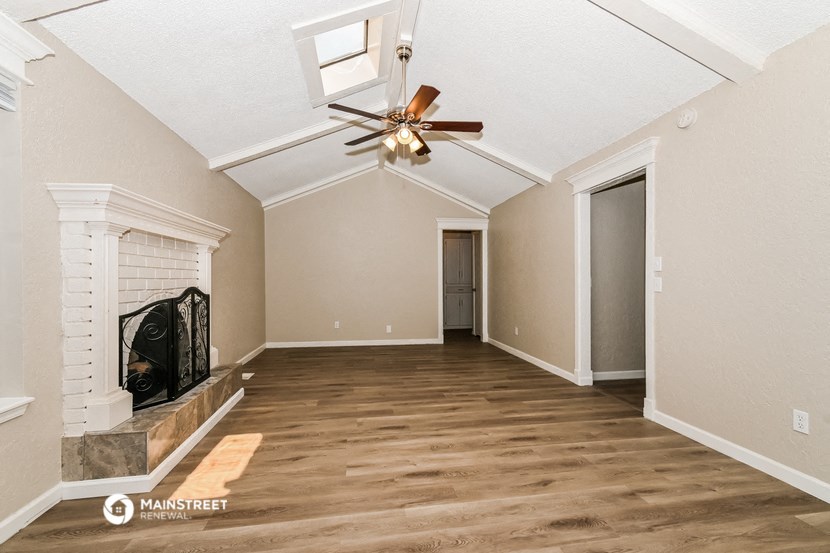 an empty living room with a ceiling fan and a fireplace