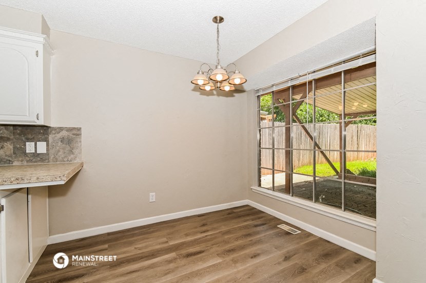 an empty living room with a large window and a kitchen