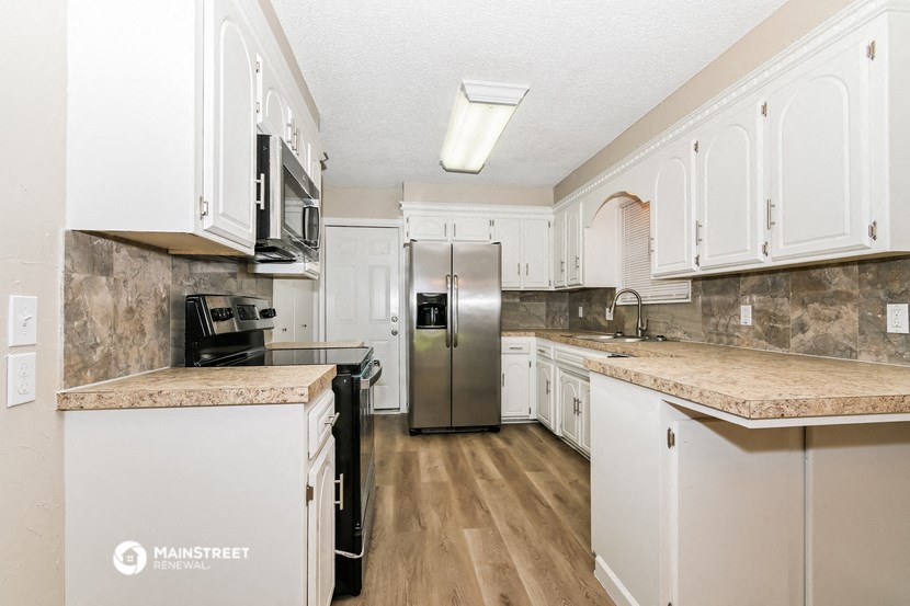 a kitchen with white cabinets and a stainless steel refrigerator