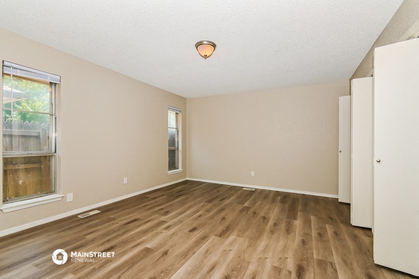 the spacious living room with hardwood flooring and a window