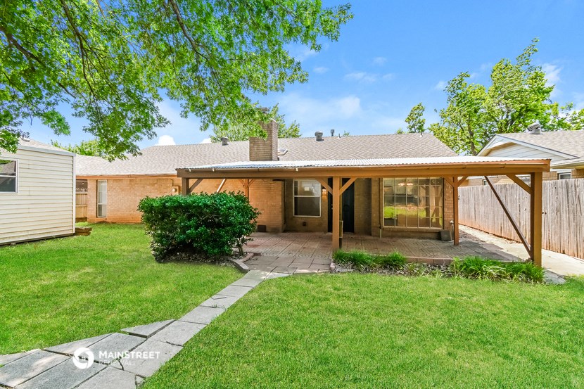 a small backyard with a covered patio and grass