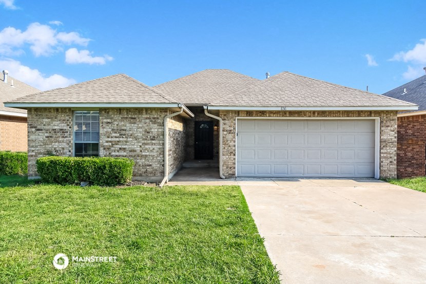 a brick house with a garage door and a lawn