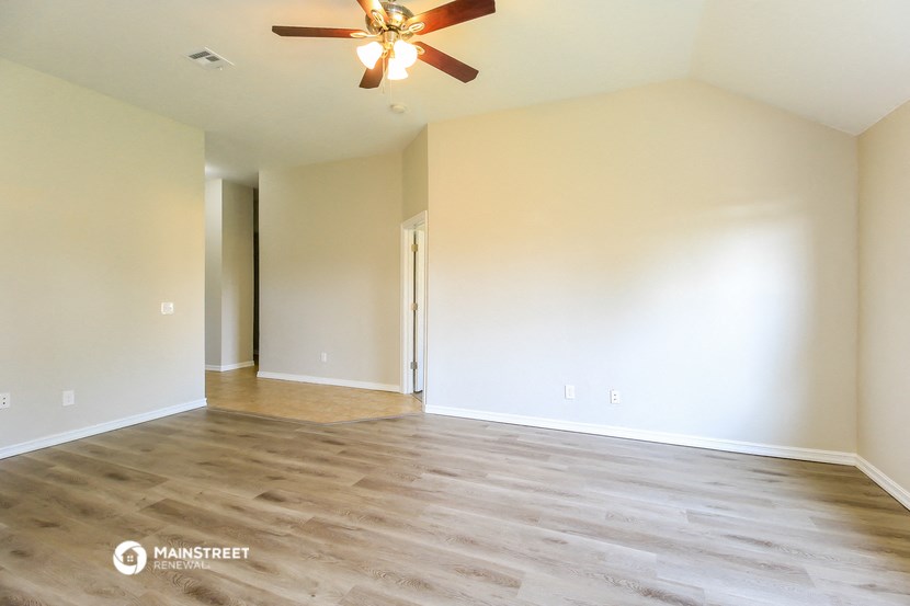 an empty living room with wood floors and a ceiling fan