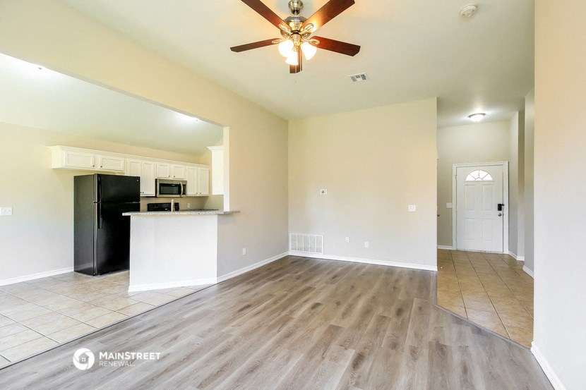 an empty living room and kitchen with a ceiling fan