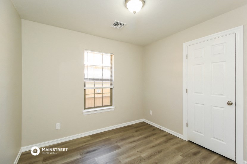 the interior of a bedroom with wood flooring and a white door