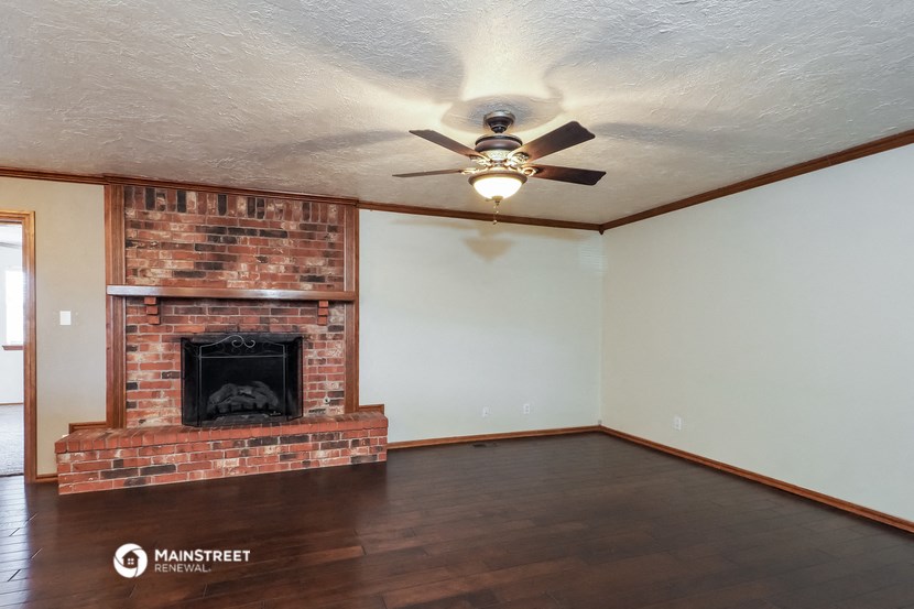 a living room with a brick fireplace and a ceiling fan