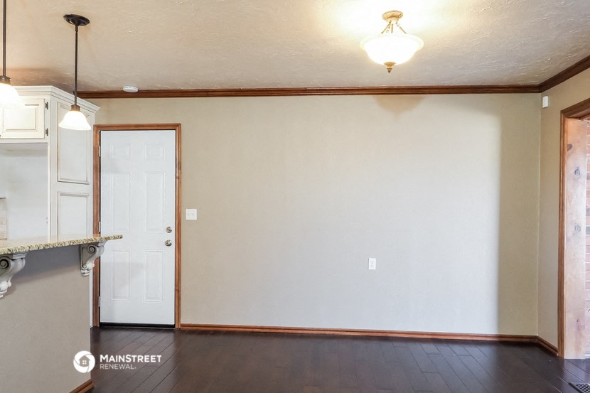 an empty living room with a white wall and a kitchen