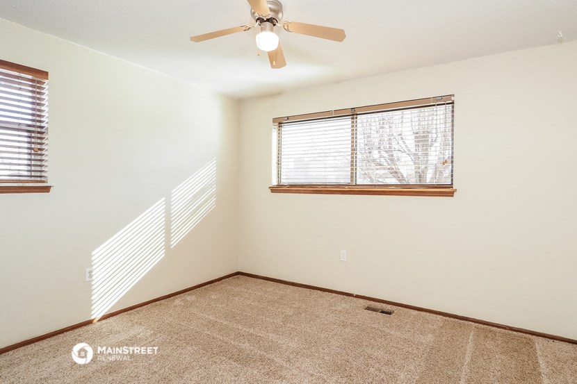 the living room is spacious and has a ceiling fan