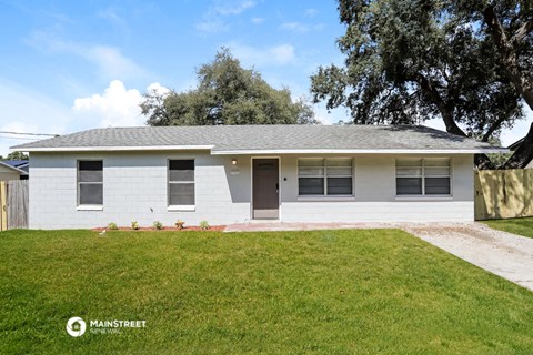a white house with a lawn and a tree